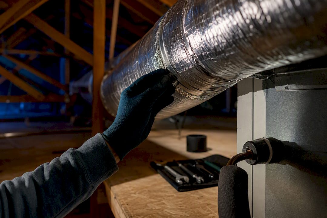 Technician inspecting attic HVAC duct connection