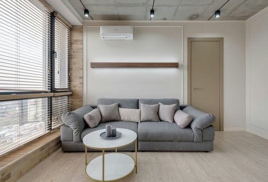Modern living room with grey sofa and wall-mounted air conditioning unit providing heating
